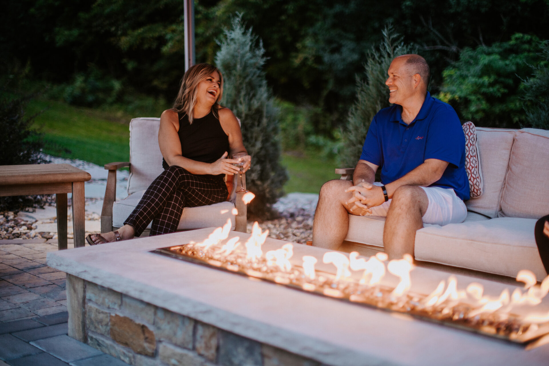two people laughing by a fire pit
