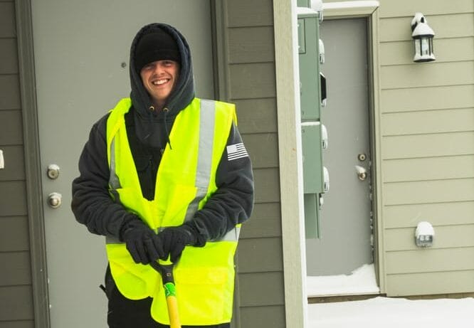 weller brothers employee smiling while shoveling snow