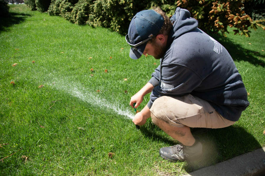 weller brothers lawn technician adjusting a sprinkler head