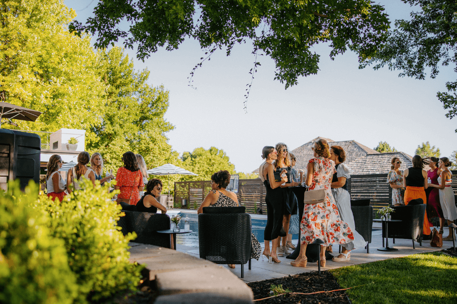 women standing at cocktail tables near a pool