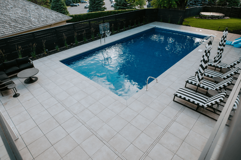porcelain paver patio with a pool and black and white outdoor loungers