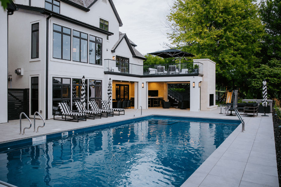 outdoor pool at a white home with black and white furniture and outdoor living space