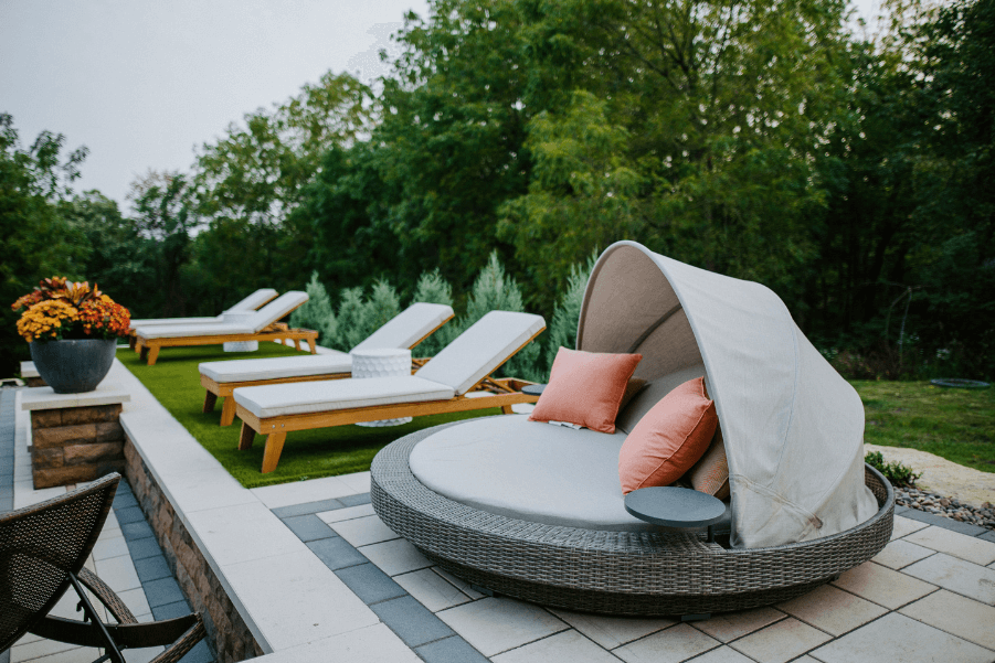 loungers near a pool on a paver patio