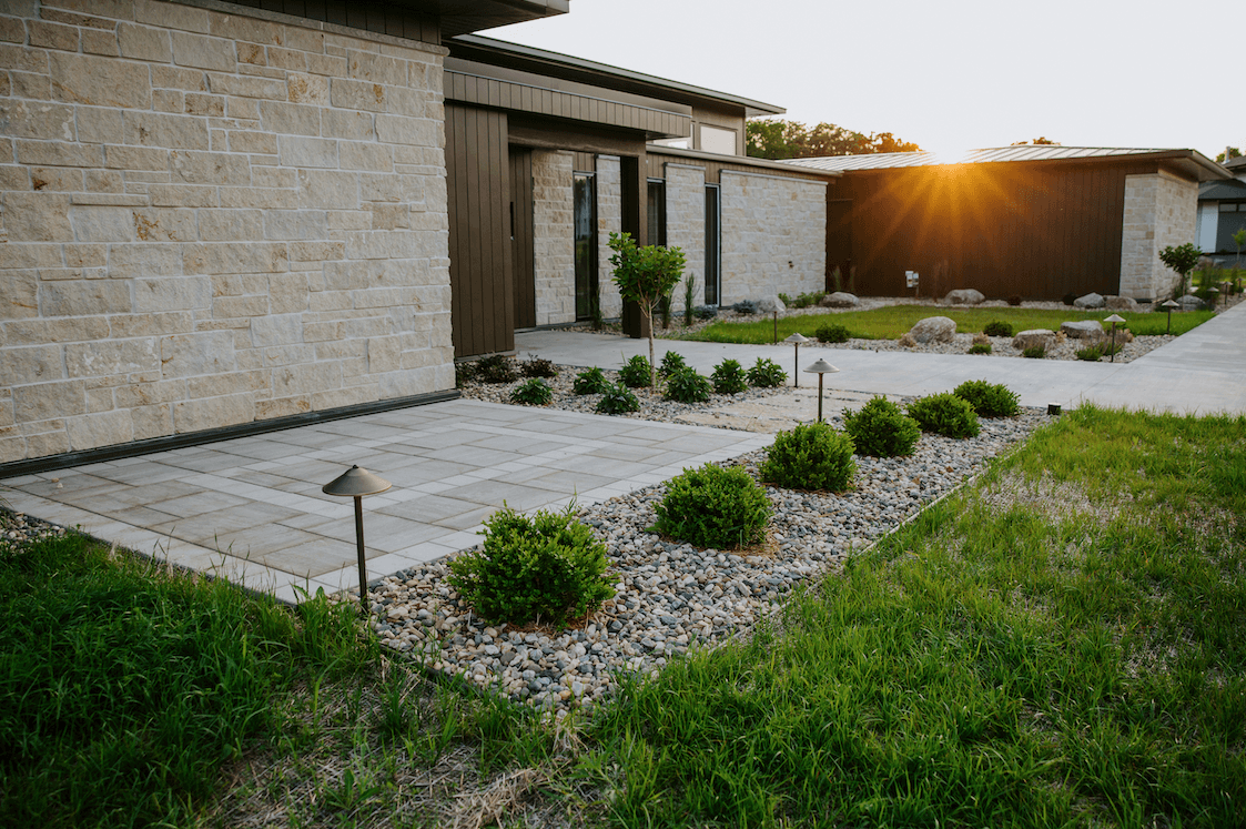 modern rochester, mn home with paver patio, landscape lighting, and rock beds
