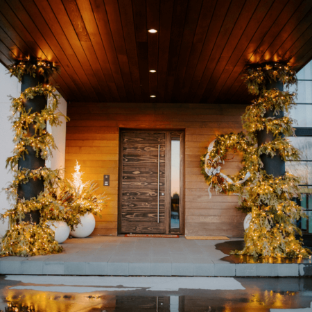 front porch of a home with garland, holiday planters, and wreath