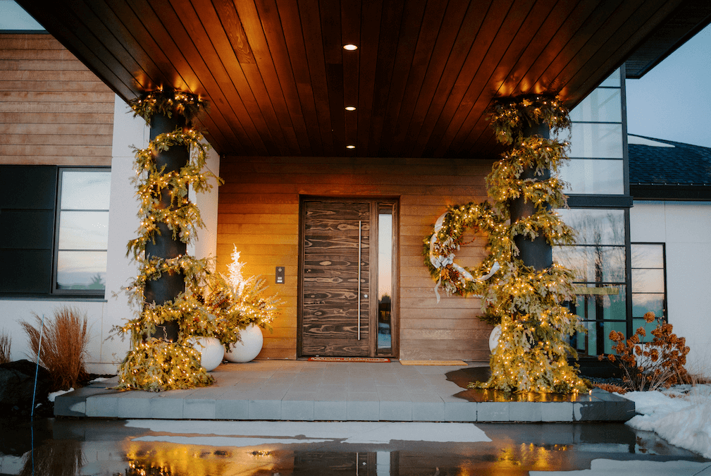 front porch of a home with garland, holiday planters, and wreath