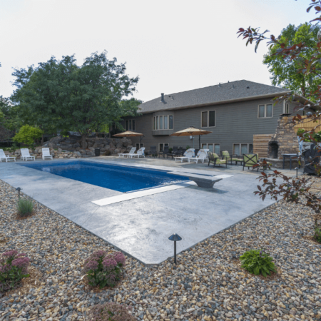 outdoor pool surrounding by a concrete patio and a rock bed