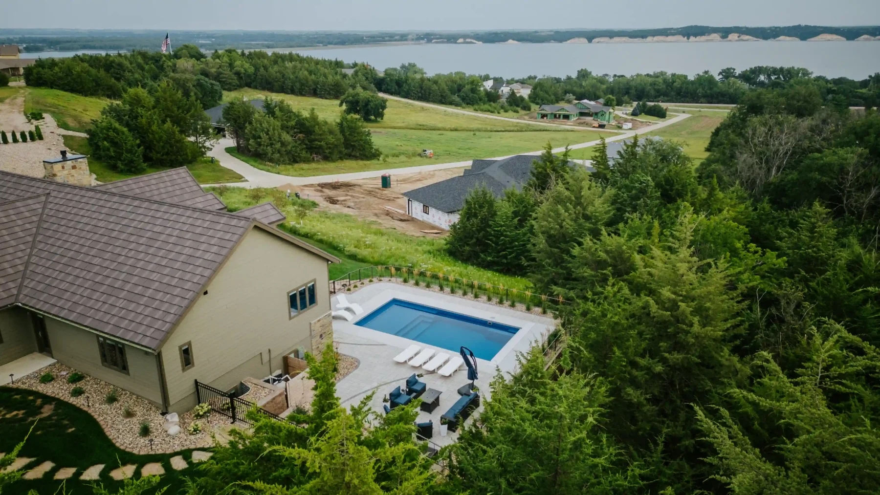 a home with a pool, surrounding landscaping, and a large retaining wall overlooks the missouri river